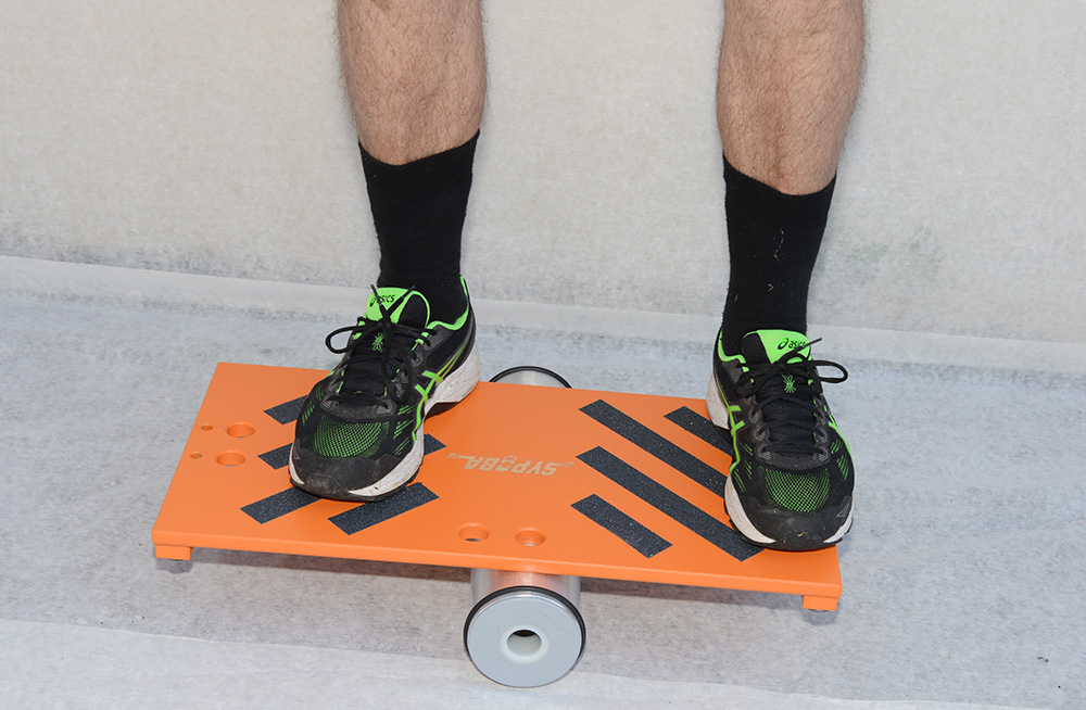 Ein Kunde balanciert stehend auf einem orangen Balance-Gerät.